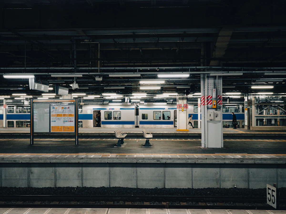 An orange passenger train waiting at a British railway station platform