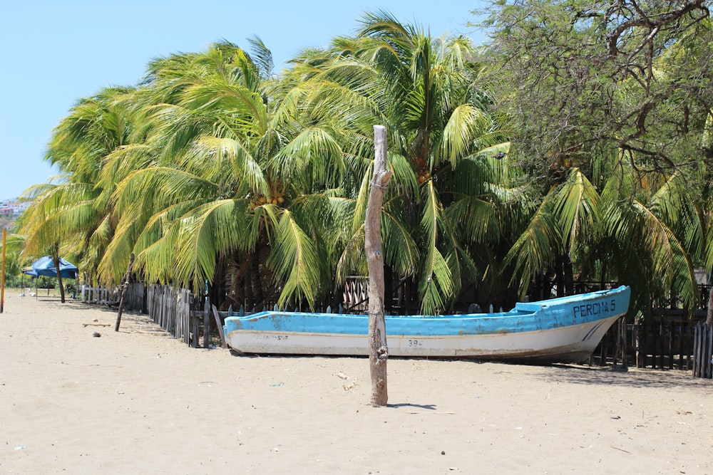 a blue and white boat sitting on top of a sandy beach