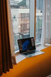 Various refurbished laptops displayed on a wooden desk near a window showing an Amiens street view.