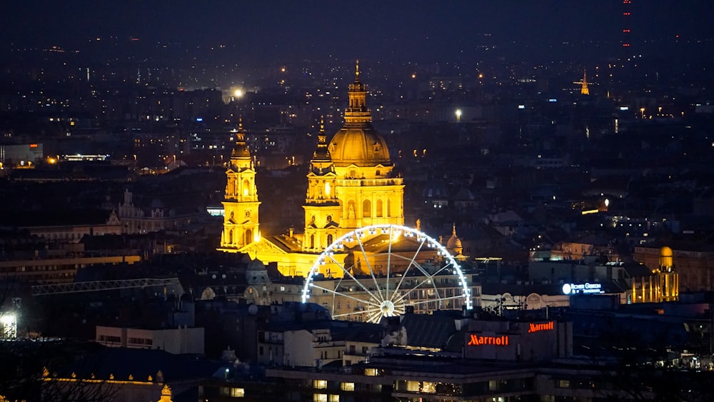 a city at night with a ferris wheel in the foreground