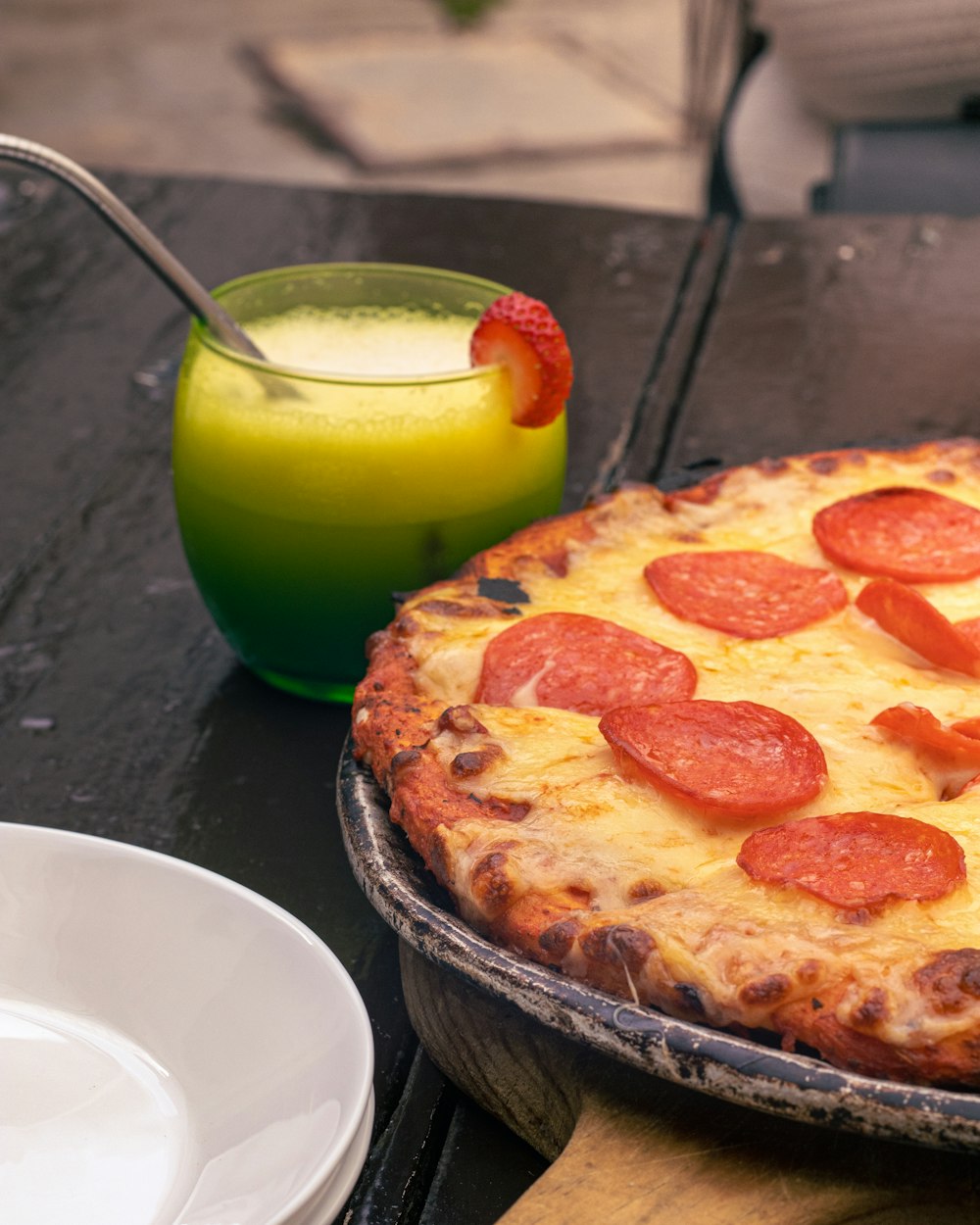 a pepperoni pizza sitting on top of a pan next to a drink
