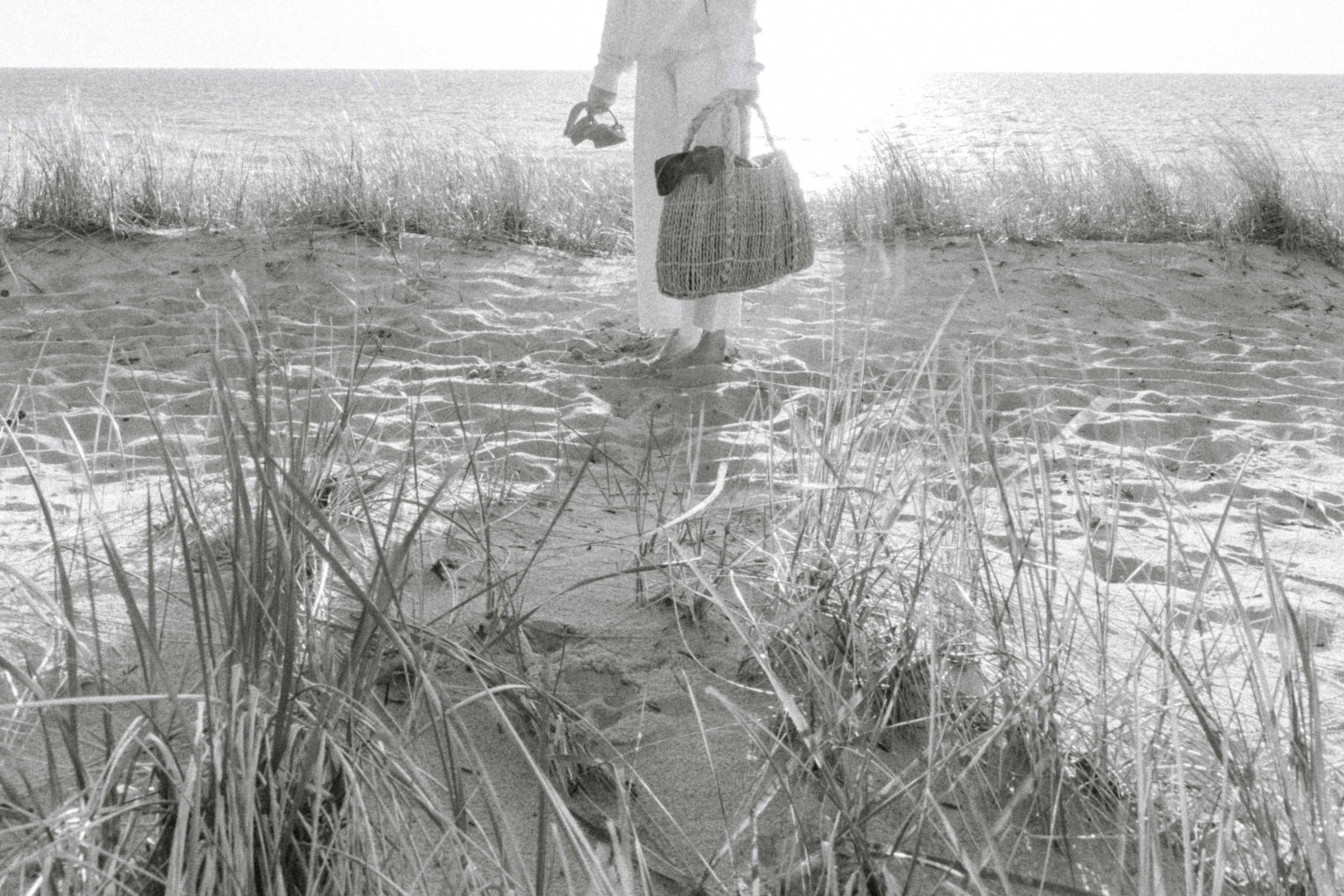 a black and white photo of a person standing on a beach