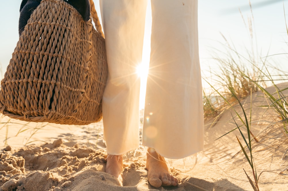 a woman in white pants holding a straw bag