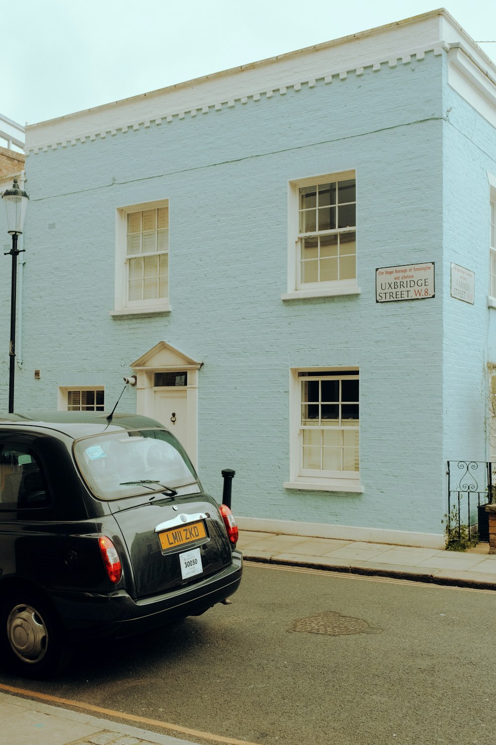 a small black car parked in front of a blue building