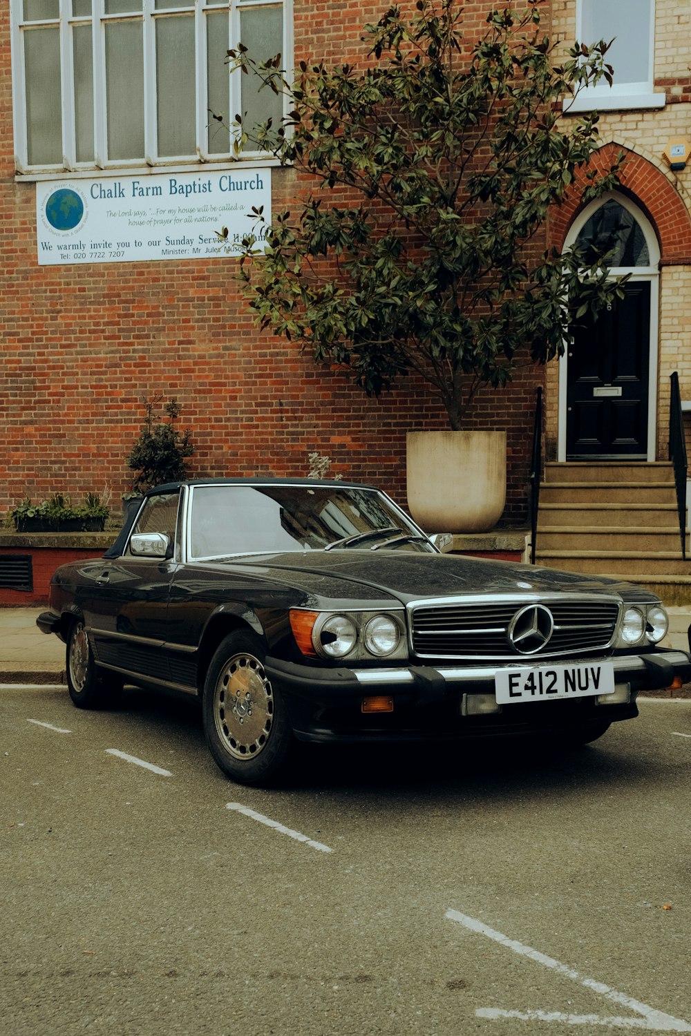 a black car parked in front of a brick building