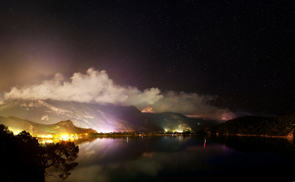 a night scene of a lake with mountains in the background