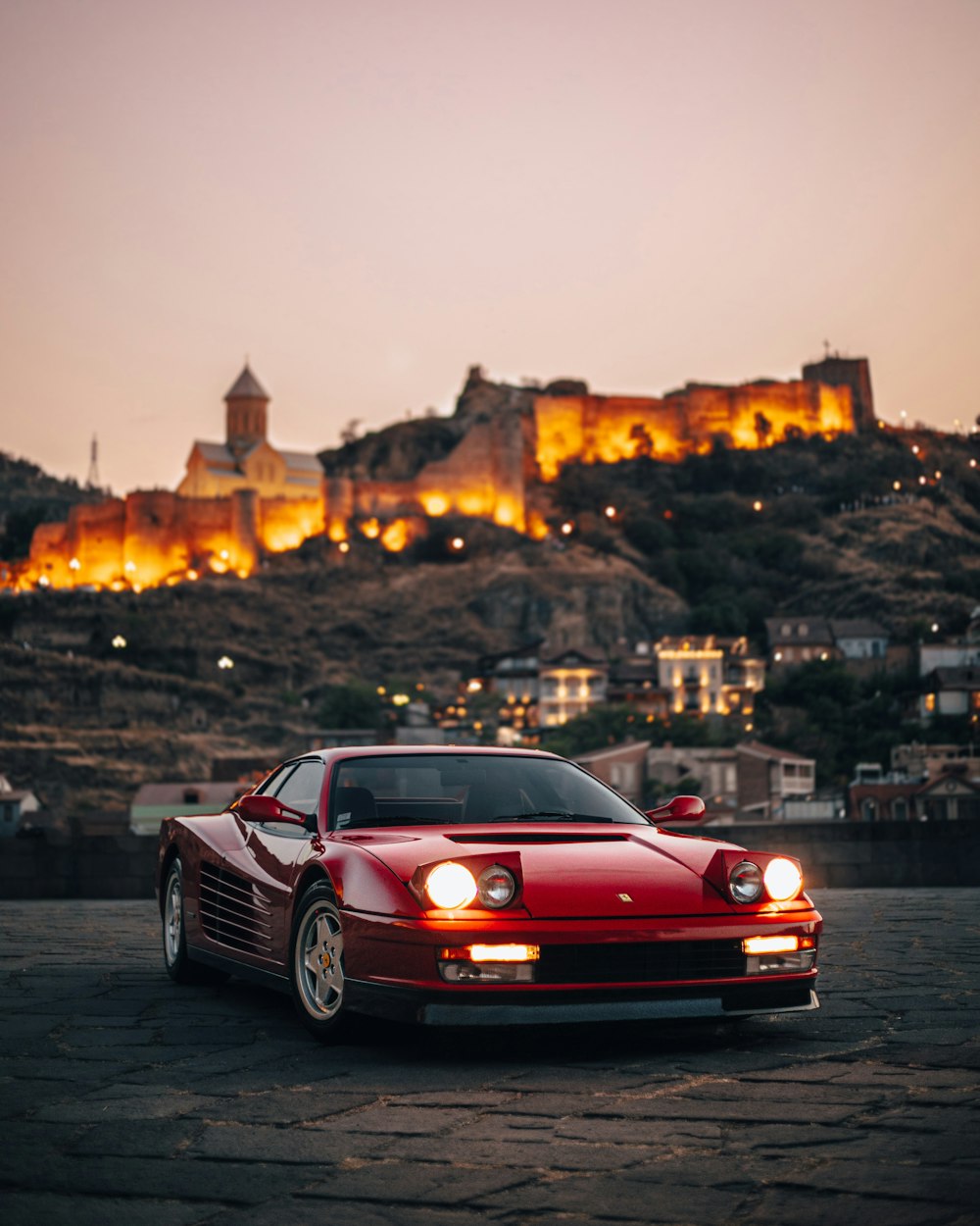 um carro esportivo vermelho estacionado em frente a um castelo