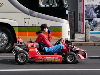 a man in a red shirt is driving a small toy car