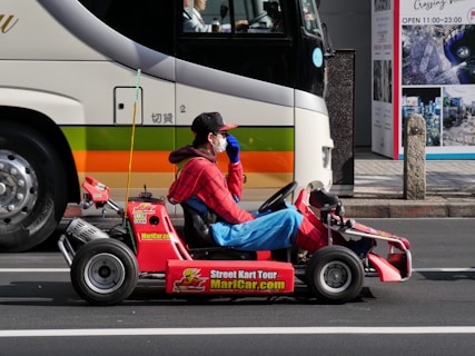 a man in a red shirt is driving a small toy car
