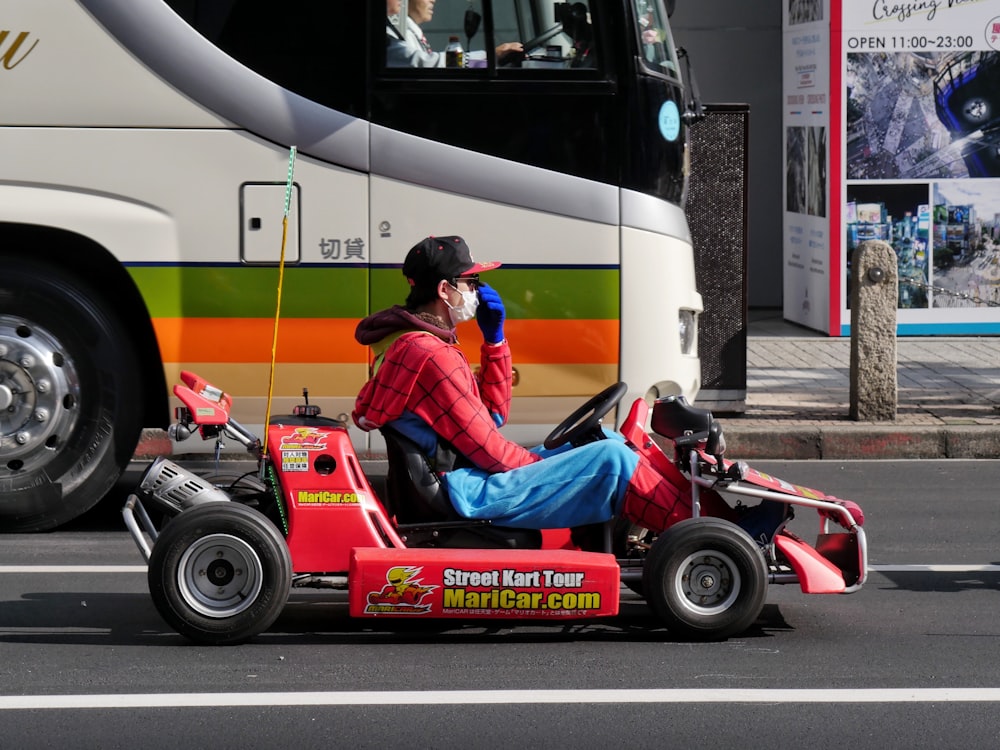 a man in a red shirt is driving a small toy car