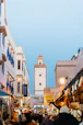 A smiling guide leading a small group through a vibrant Moroccan market street.