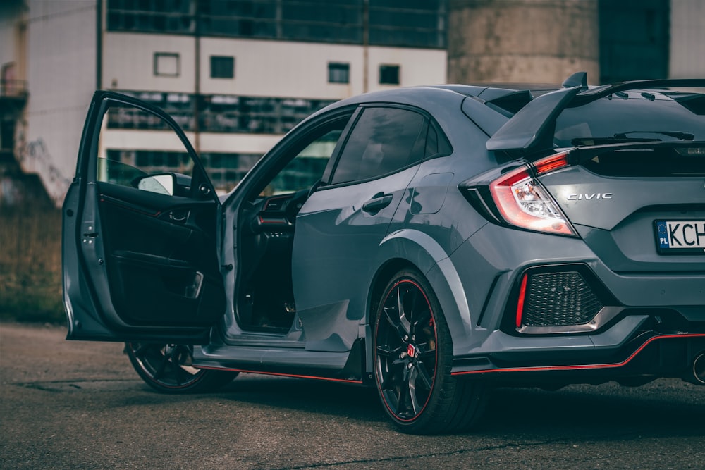 a grey honda civic hatchback parked in front of a building