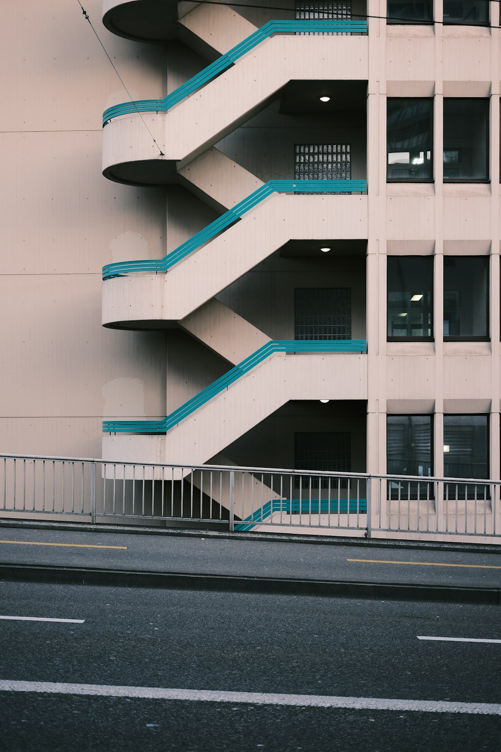 a tall white building with blue balconies next to a street