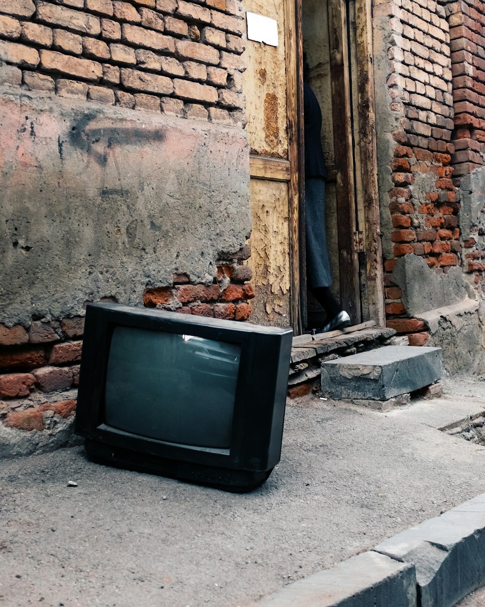Un televisor sentado en el suelo frente a un edificio de ladrillo
