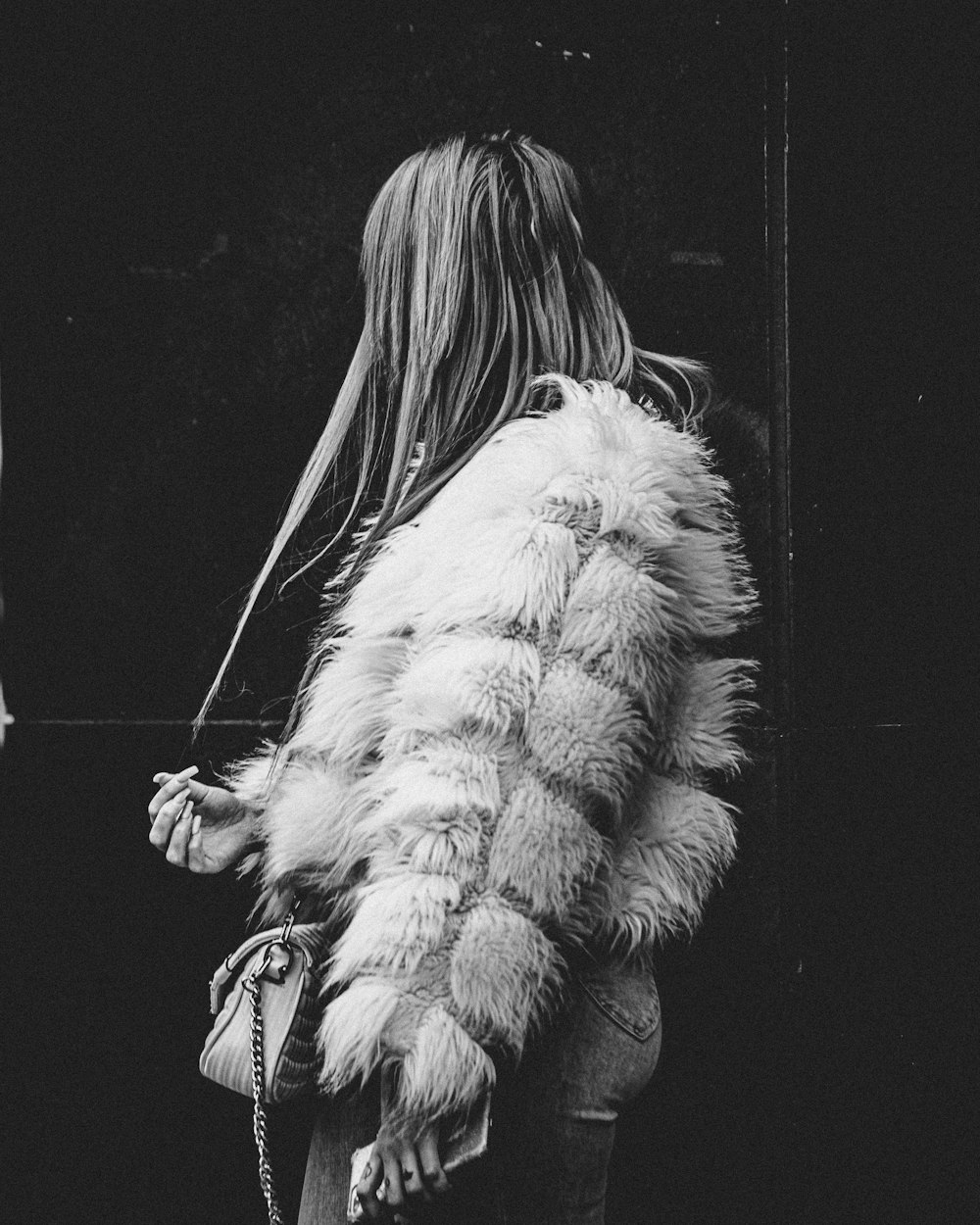 a woman walking down a street carrying a purse