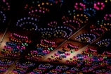A ceiling adorned with a series of colorful, decorative lights forming intricate patterns. The lights emit in vivid hues, arranged in swirling, circular shapes that add a whimsical and festive atmosphere.