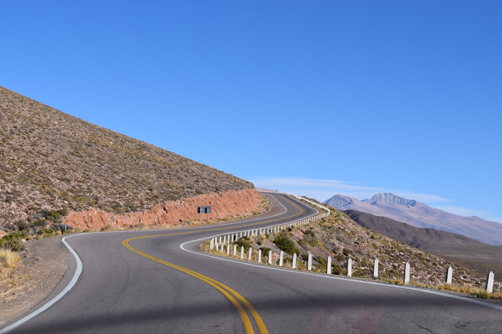 a curved road with a mountain in the background