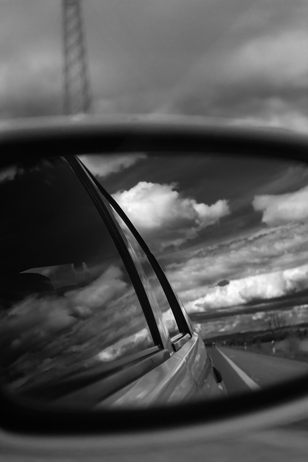 a rear view mirror on a car with clouds in the background