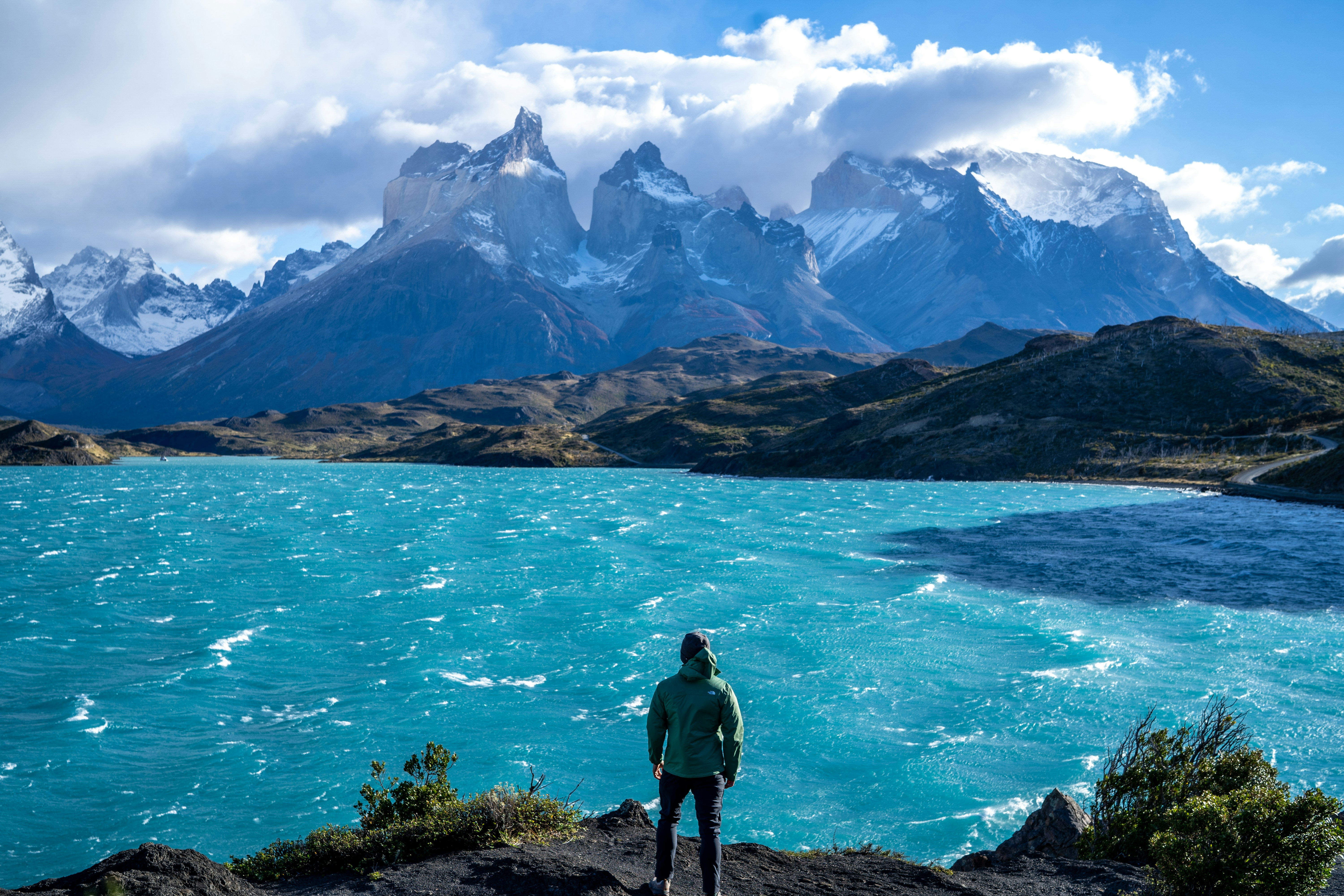 a man standing on top of a mountain next to a lake, 