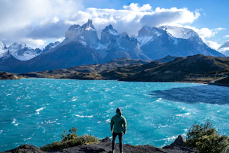 a man standing on top of a mountain next to a lake