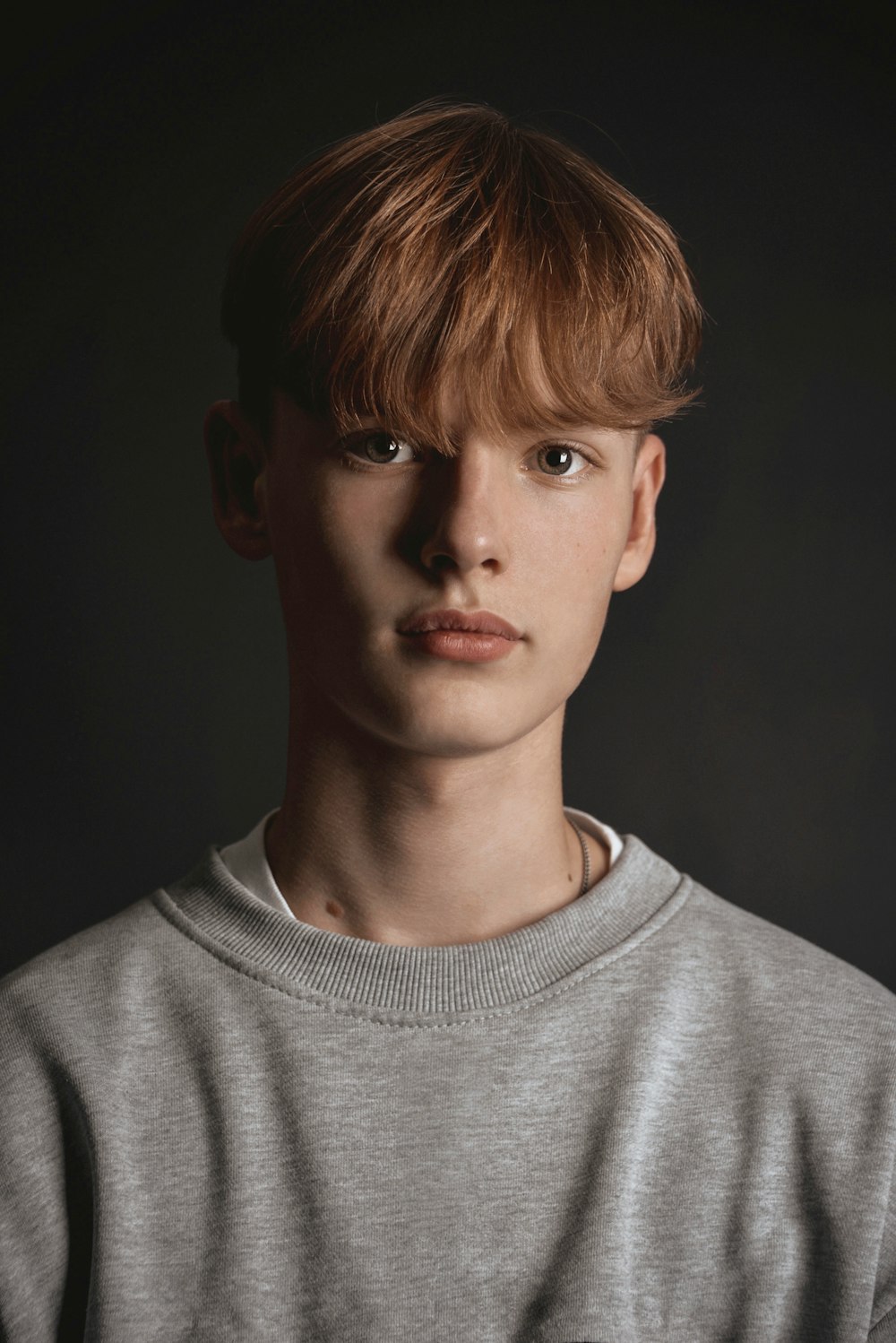 a young man with red hair and a grey shirt