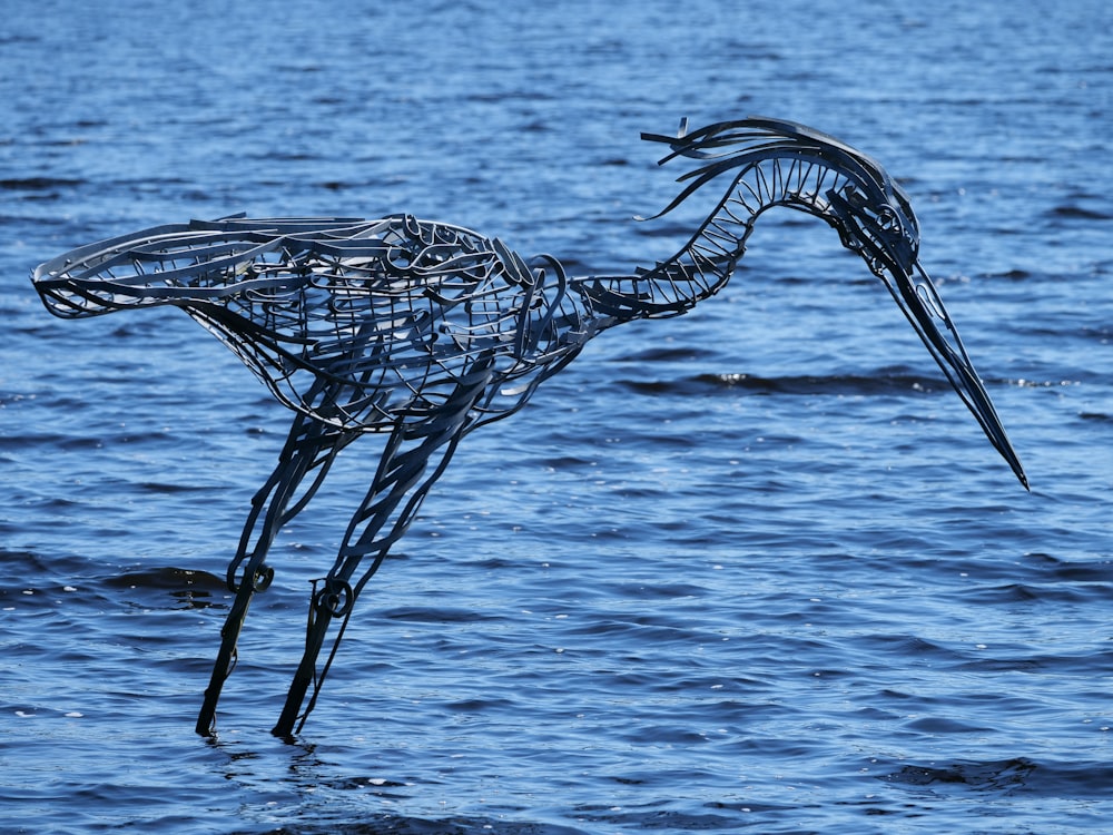 a metal bird sculpture floating on top of a body of water