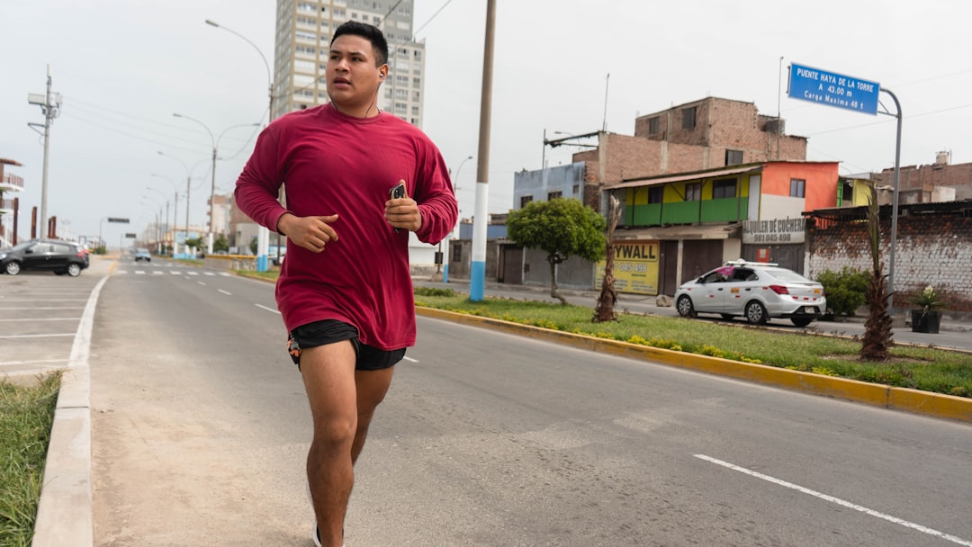 a man running down the street in a red shirt, boy running with red t-shirt