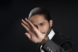 a man in a tuxedo is holding his hand up