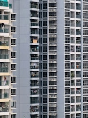 Close-up of a balcony screen installed on a sunny day with urban buildings in the background.