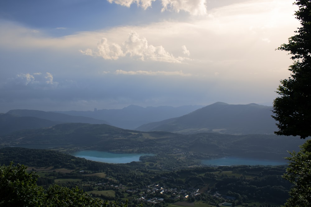 a view of a lake and mountains from the top of a hill