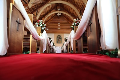 a church with a red carpet and white drapes