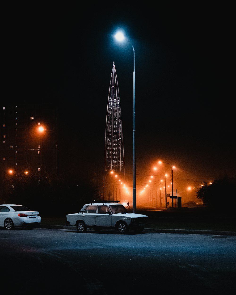 two cars parked in a parking lot at night