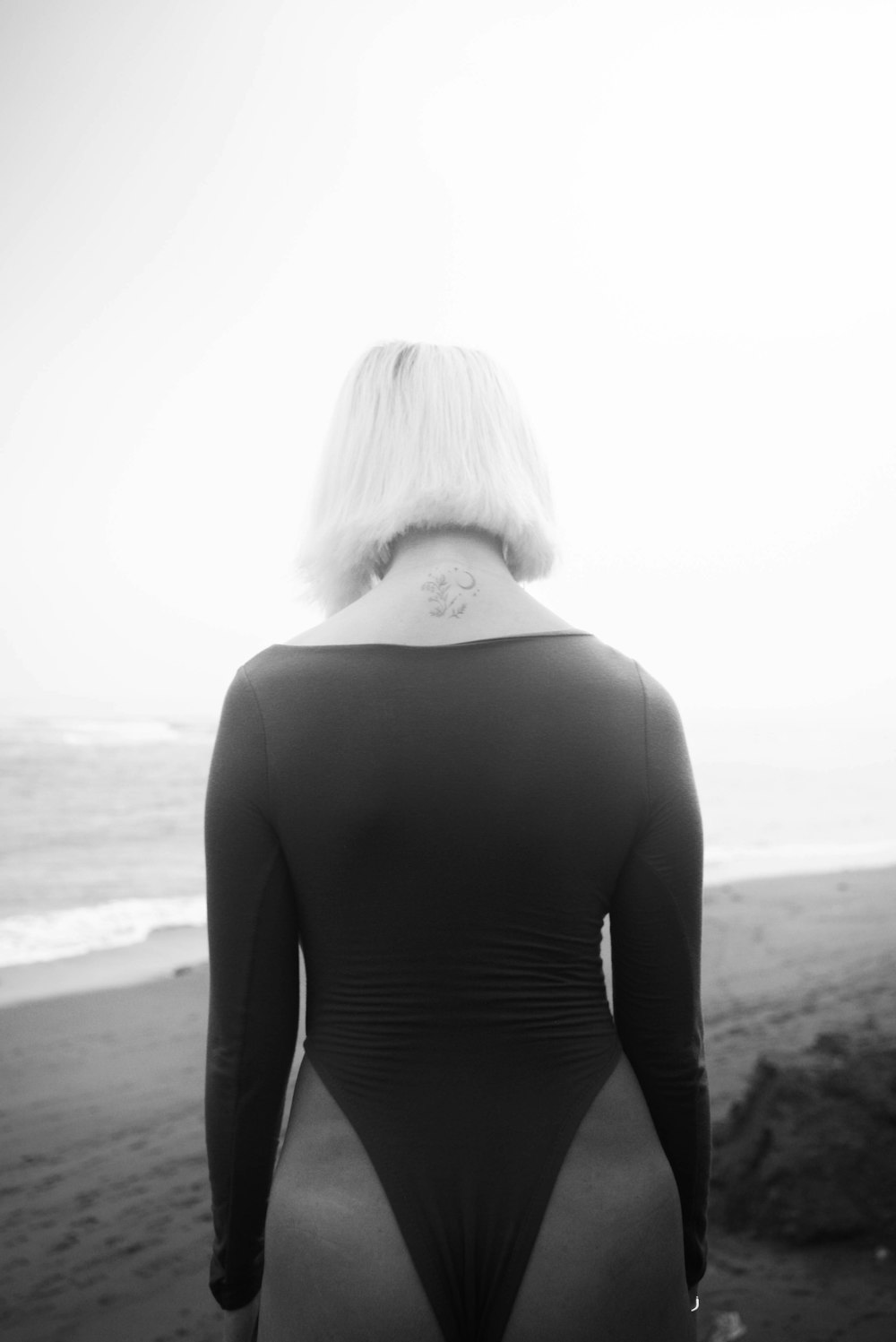a woman in a bodysuit standing on a beach