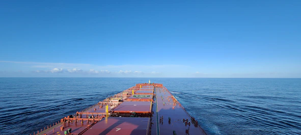 A large cargo ship navigating open seas under clear skies.