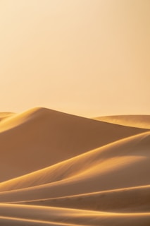 A serene natural landscape with soft sand dunes under a warm, gentle light.