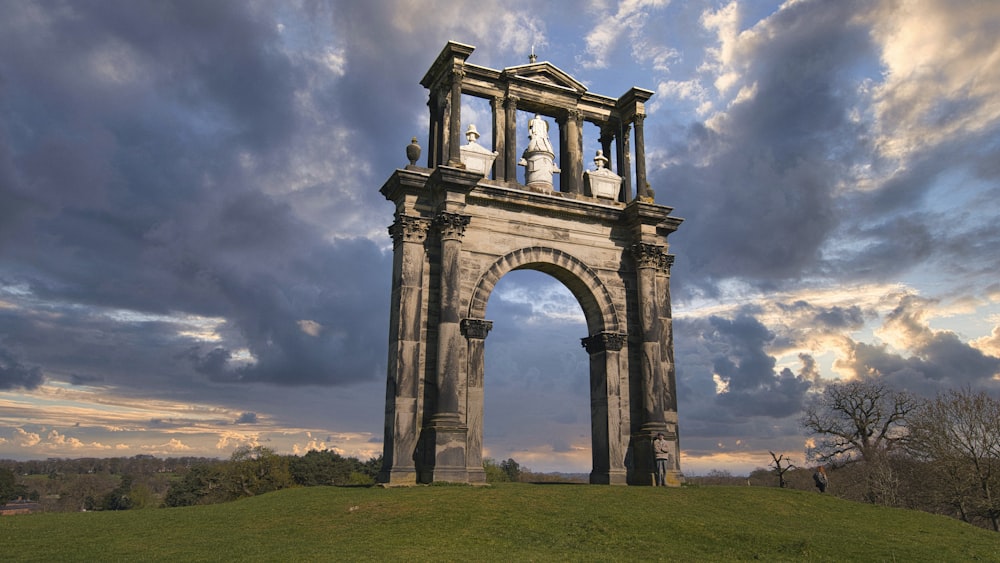 um grande arco de pedra no topo de uma colina verde