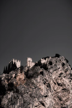 A towering stone fortress embedded in steep, dark cliffs under a stormy sky.