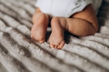 A close-up of baby feet resting on a soft blanket.