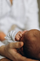 A close-up of a newborn's tiny hand held by a parent.