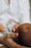 A close-up view of a person gently holding a newborn baby. The baby's tiny hand is curled around the person's finger, conveying a sense of tenderness and care.