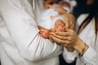 Baby's tiny feet slipping into soft sole brown oxfords with a gentle hand helping.