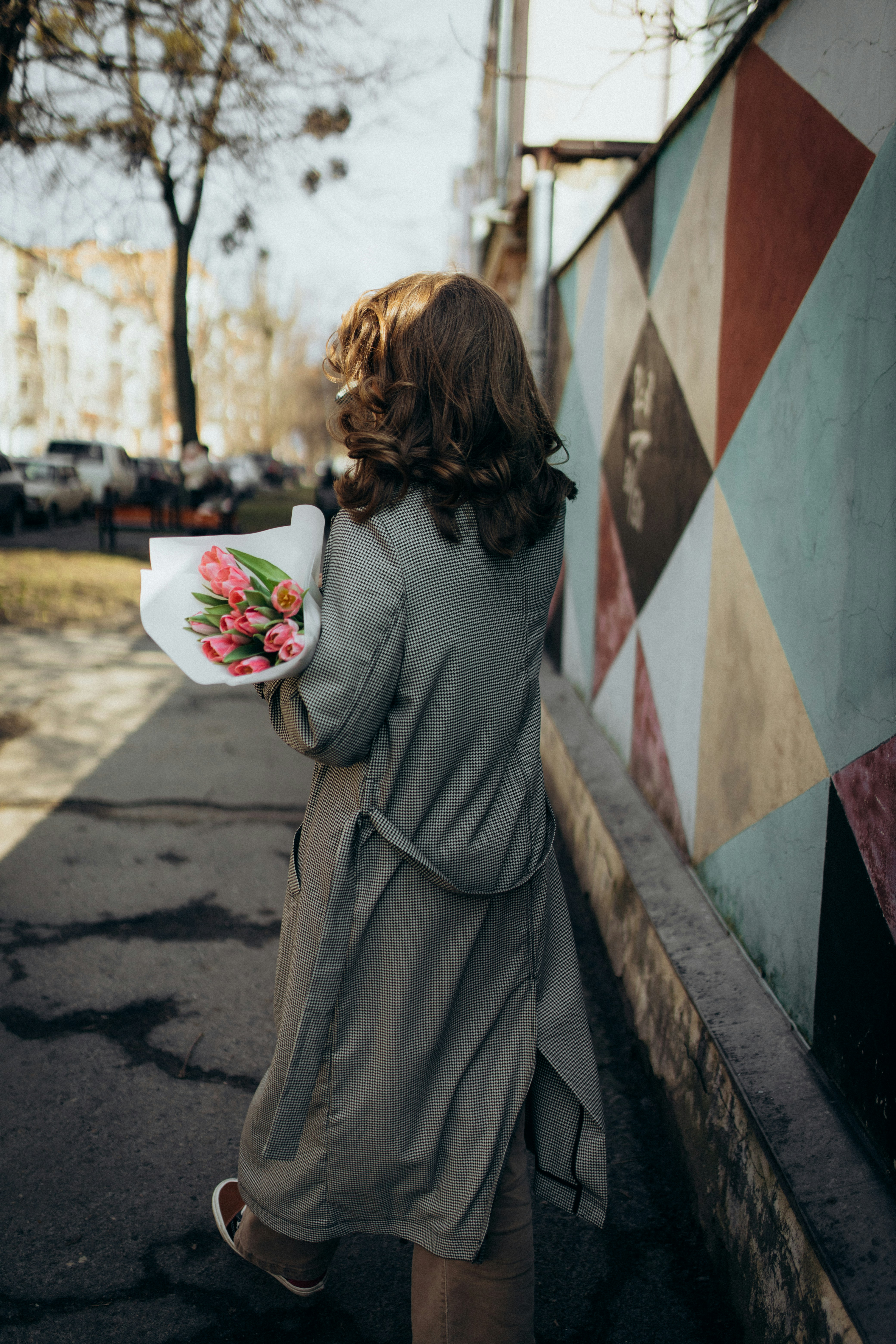 a woman walking down a street holding a plate with flowers on it