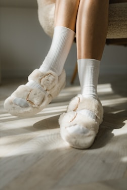A cozy, stylish pair of shoes resting on a wooden floor beside a window with soft natural light.
