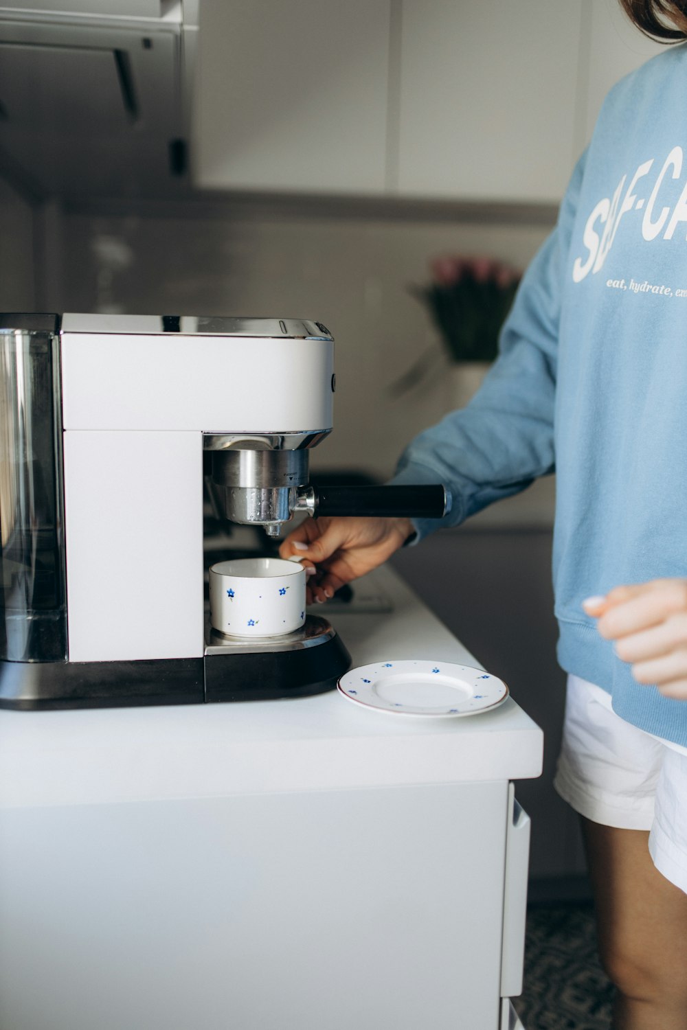 a woman in a blue shirt is using a coffee maker