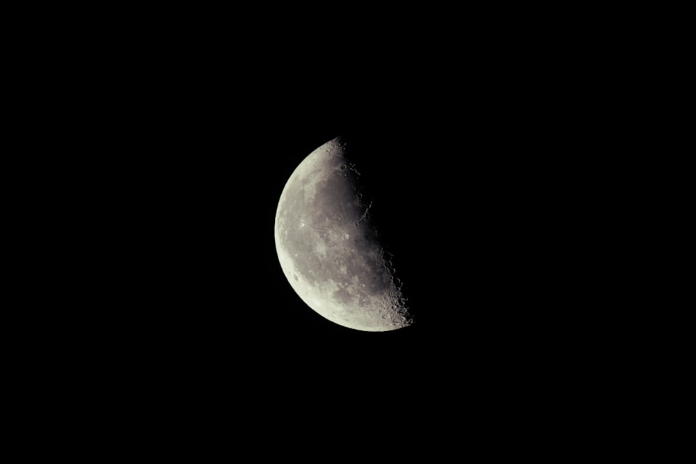 a half moon is seen in the dark sky