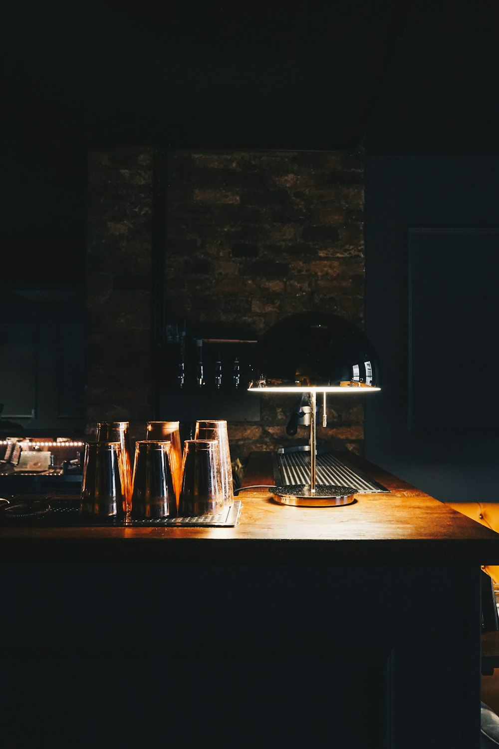 a wooden table topped with glasses and a lamp
