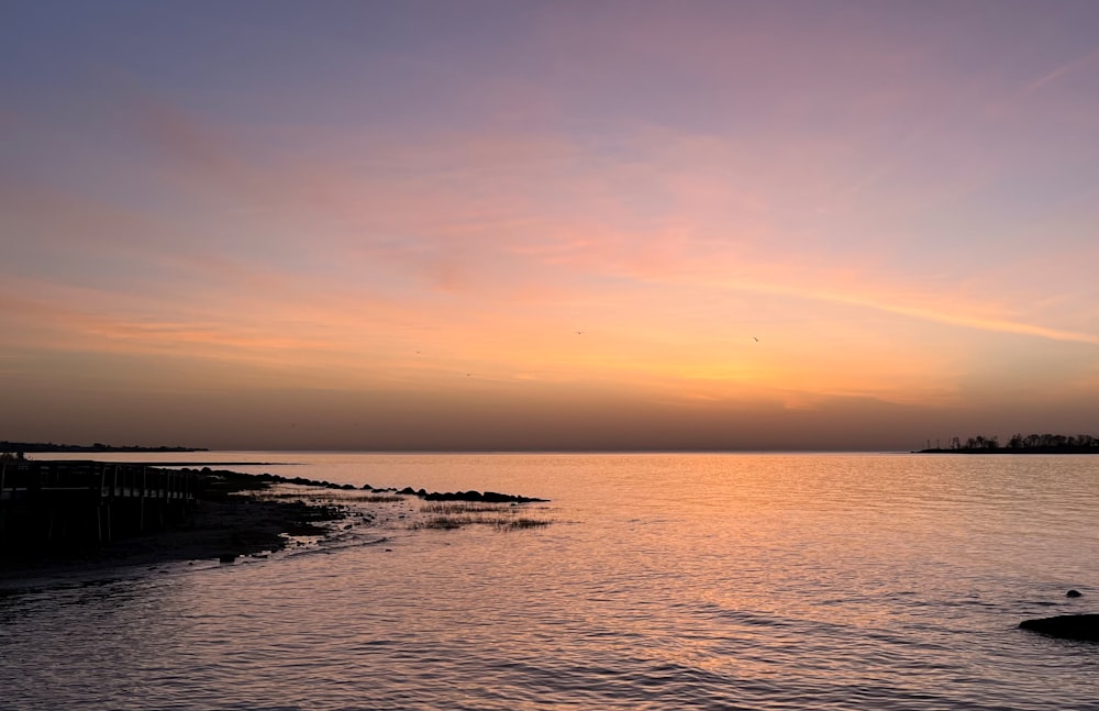 a sunset over a body of water with a boat in the distance