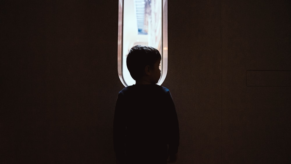 a person standing in front of a window in a dark room