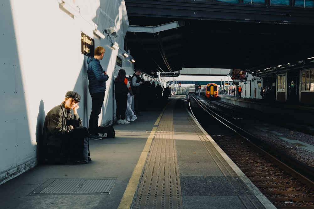a man sitting on a train platform next to a train