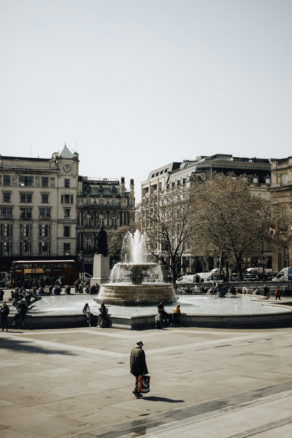 a man sitting on a bench in front of a fountain